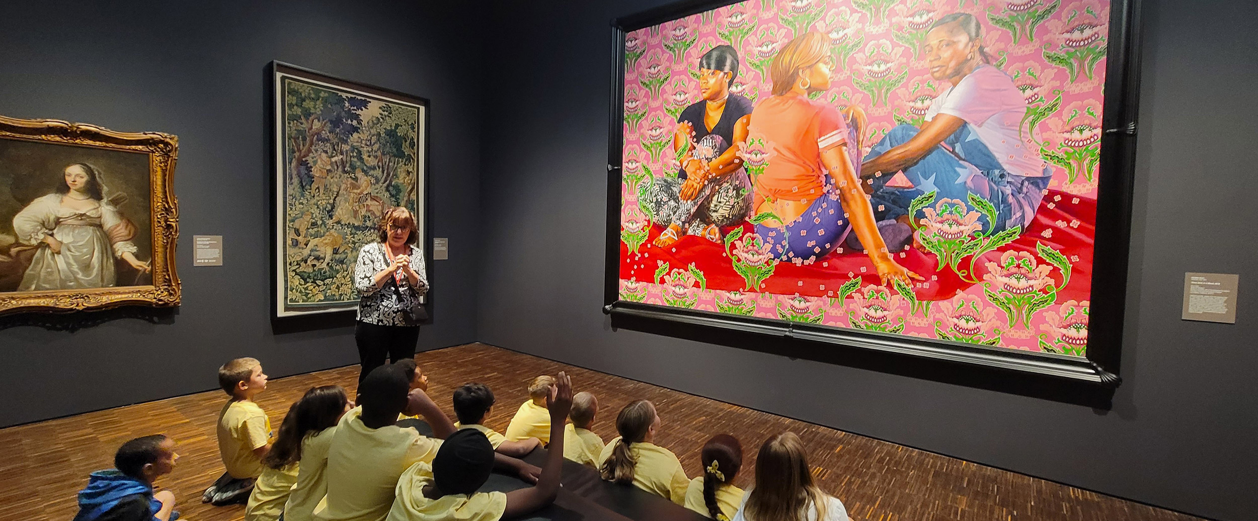 Museum staff talking to children while they look at a painting